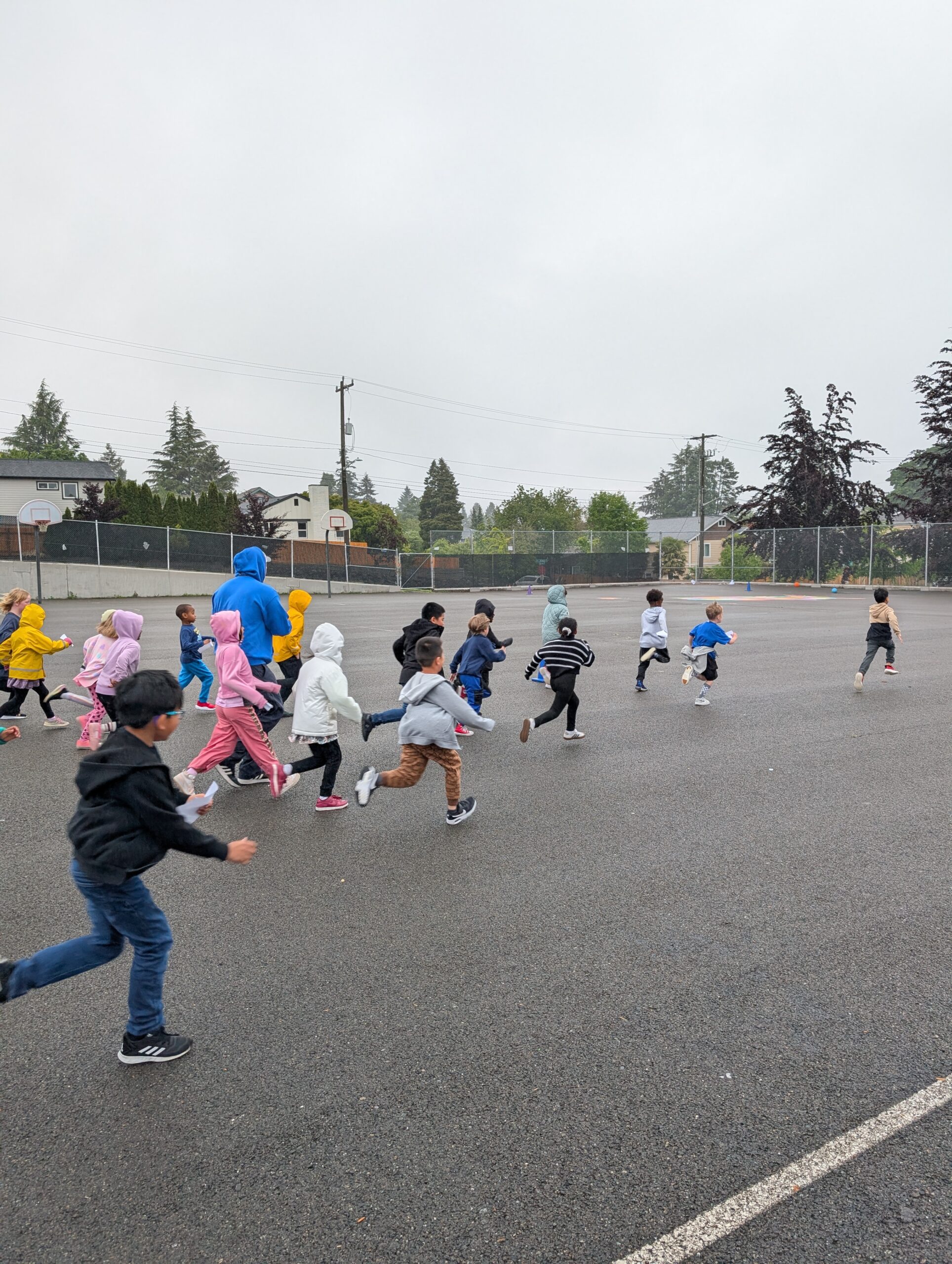 Lots of young children running across the Roxhill playground blacktop