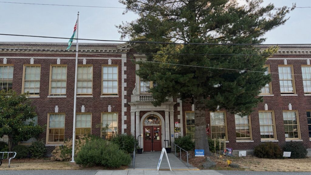 Image shows Roxhill Elementary, a brick building with large windows and a tree and flagpole in front. 