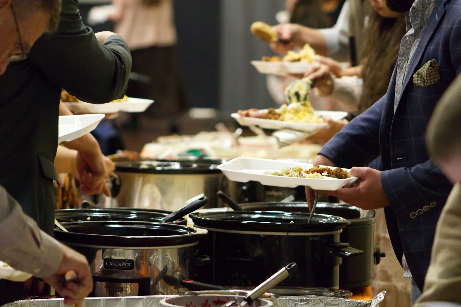 People serve themselves from a long line of dishes